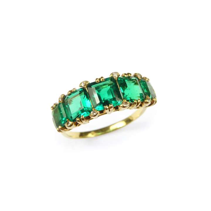 Graduated five stone emerald ring. claw set with trap-cut square Colombian emeralds